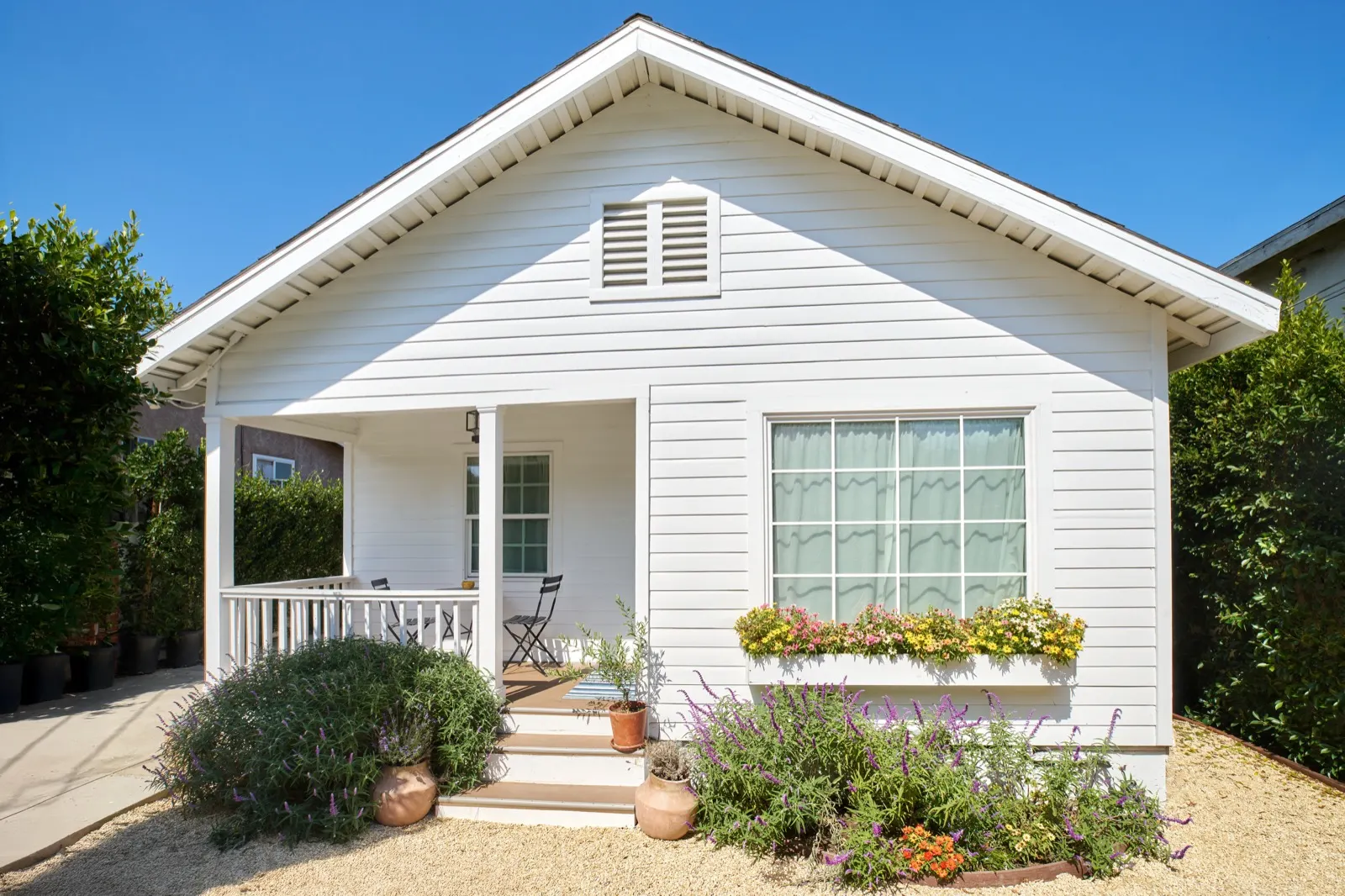 The white cottage exterior with front porch, flower boxes and lavender