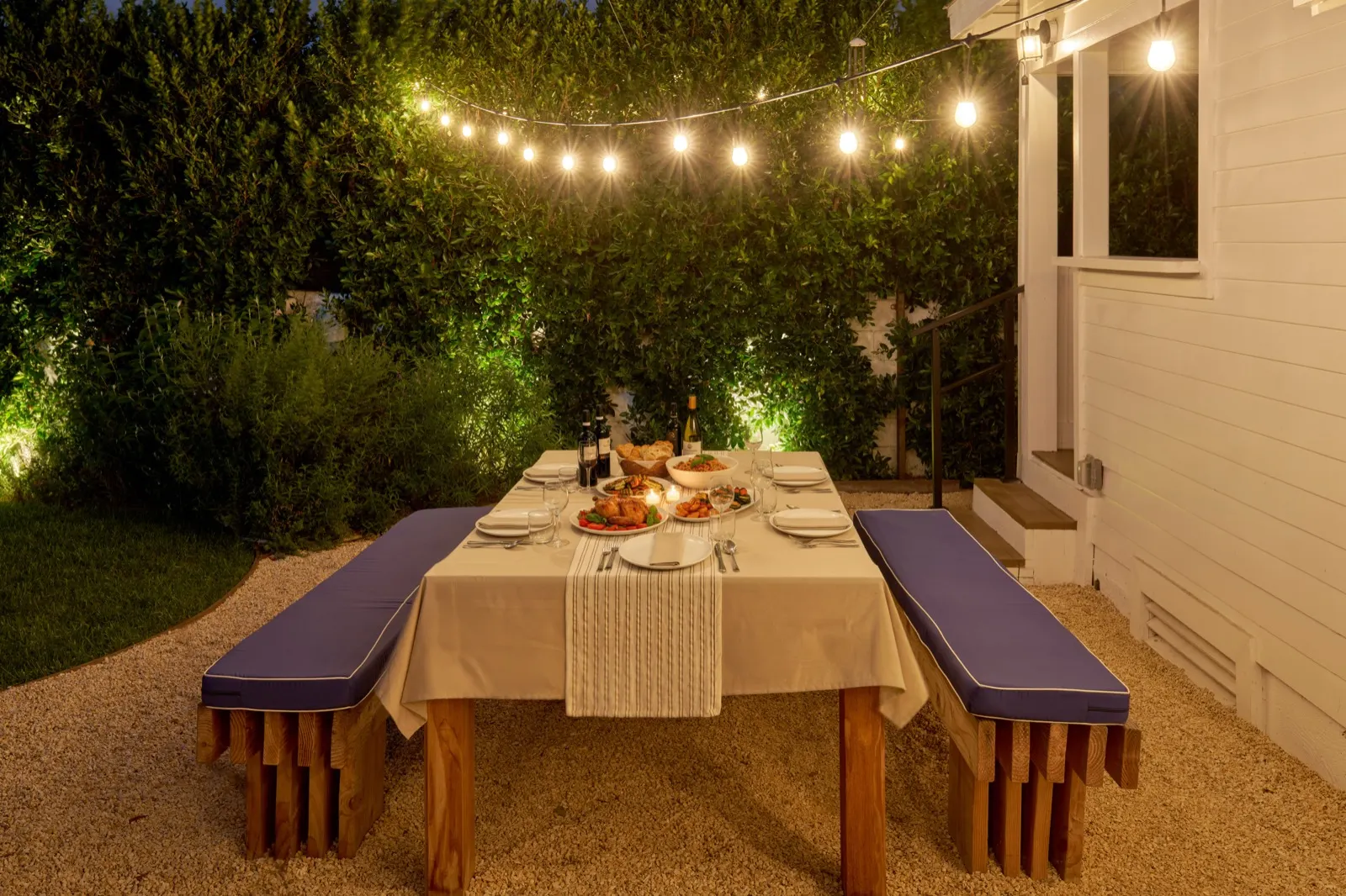 Outdoor dinner table under string lights at dusk