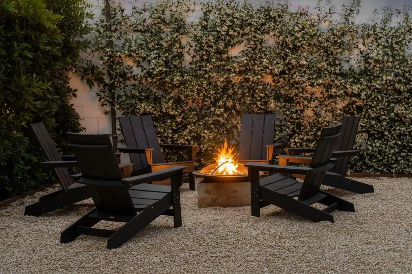 Fire pit with Adirondack chairs against a jasmine wall