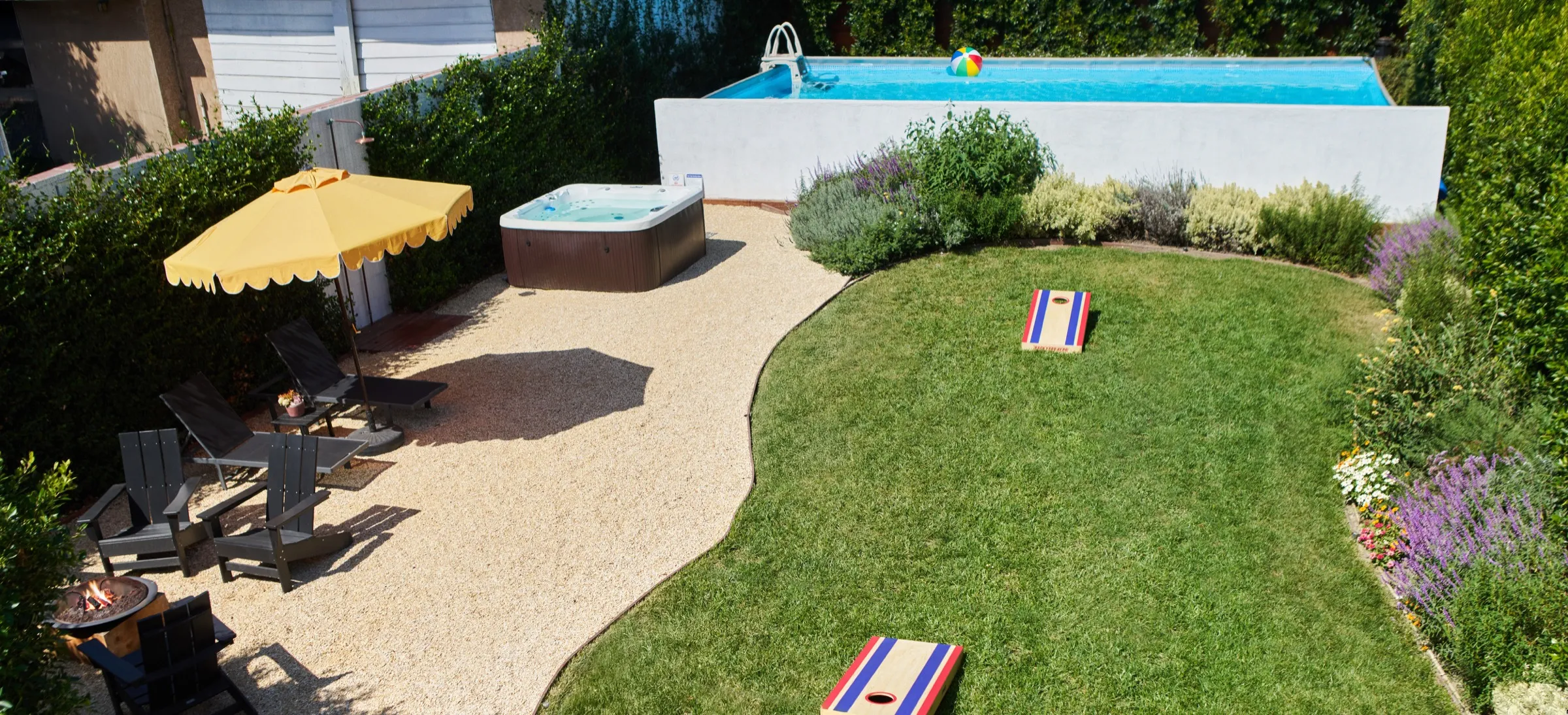 The private backyard at Casa Blanco — saltwater pool, hot tub, fire pit and lawn