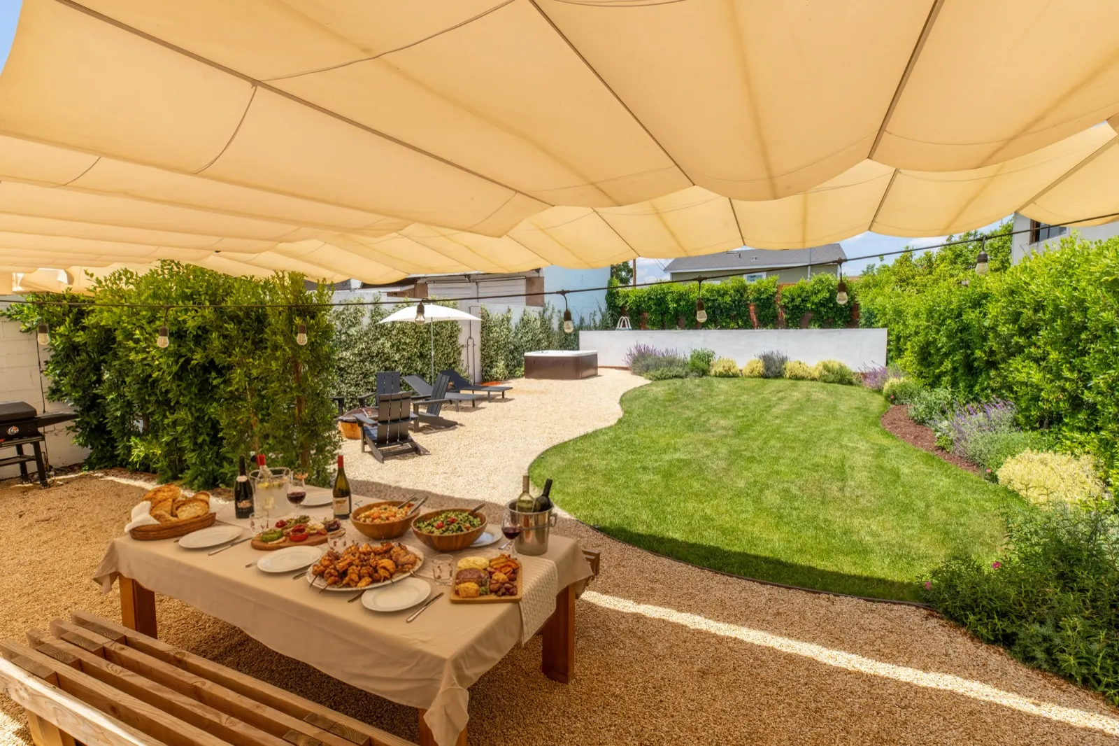 Dining table set with food and wine, lawn beyond